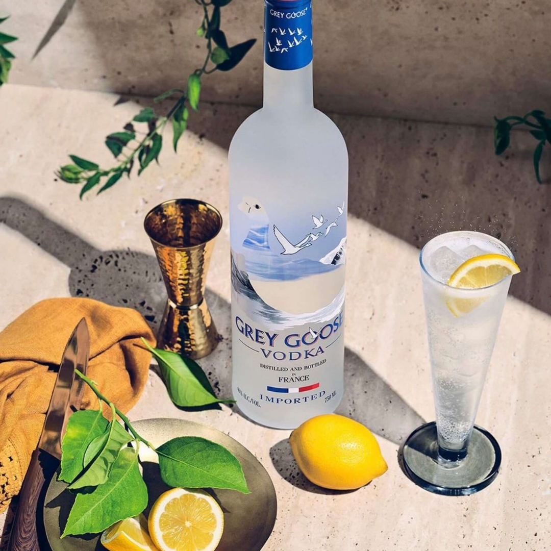 Grey Goose Vodka 750 ML bottle with a glass of vodka cocktail garnished with lemon, fresh lemons and leaves on a plate, premium vodka setup in Nepal