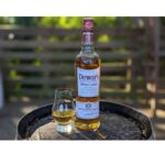 Glass of Dewar’s White Label Scotch whisky served on ice with bottle in background