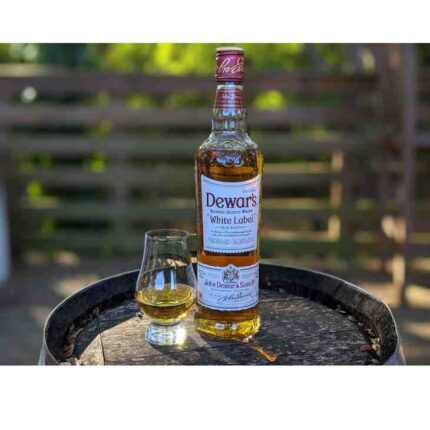 Glass of Dewar’s White Label Scotch whisky served on ice with bottle in background